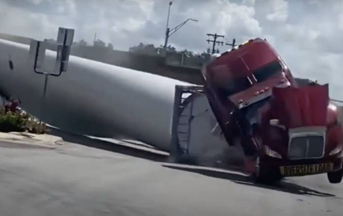 Watch Semi Trucks Hauling Large Turbine Blades Imposed by Freight Train