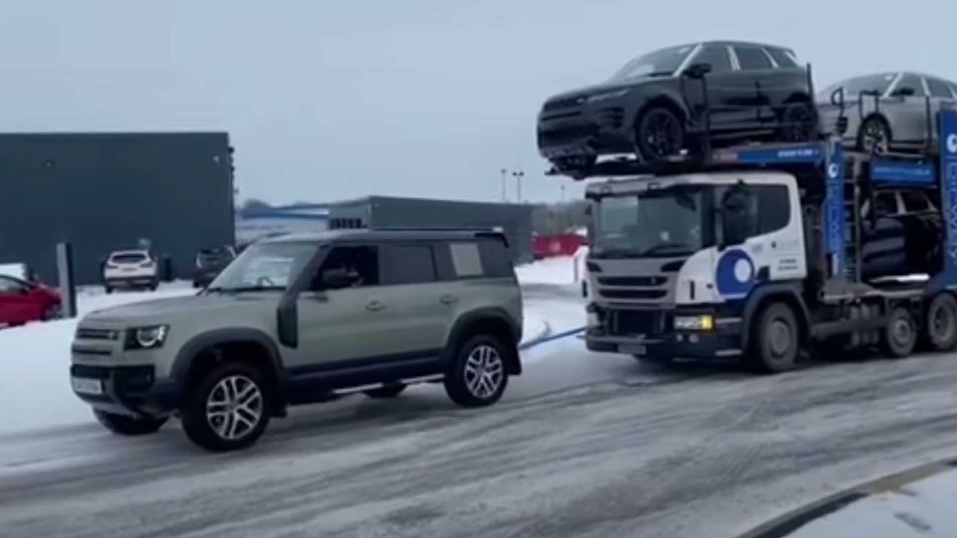 Car trailer with six Land Rovers pulled by a new Defender on Icy Road